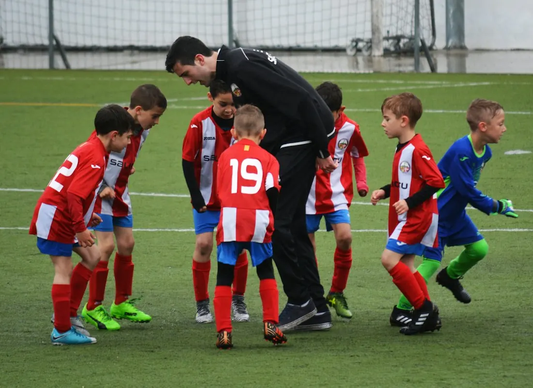 Youth soccer coach huddling with his team